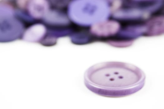 Close up of various purple button scattered on a white surface.