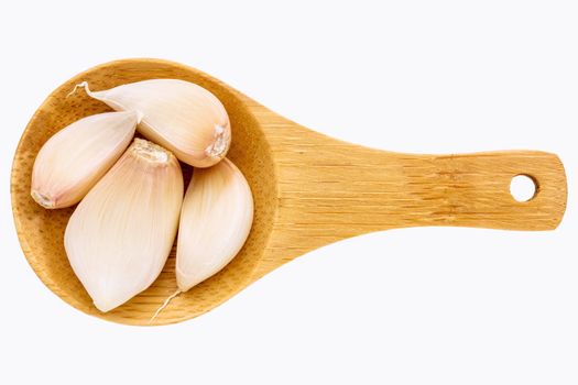 garlic cloves  on a small wooden spoon isolated on white with a clipping path