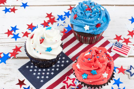 Chocolate cupcakes decorated in red, white, and blue and surrounded by stars and flags in celebration of  Independence Day.
