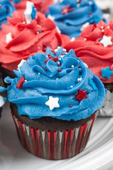 Chocolate cupcakes decorated in red, white, and blue and surrounded by stars and flags in celebration of  Independence Day.