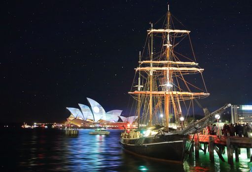 SYDNEY, AUSTRALIA - MAY 23, 2015; Sydney Opera House illuminated with colourful animated imagery during the Vivid Sydney 2015 annual public event.  Southern Swan historic nautical Tall Ship docked in foreground
