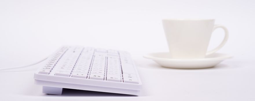 Keyboard and cup on isolated white background, side view