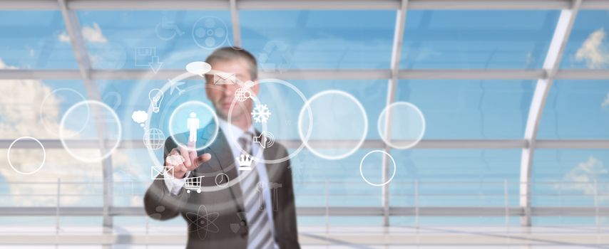 Businessman pressing on holographic screen with icons in circle on window and map background