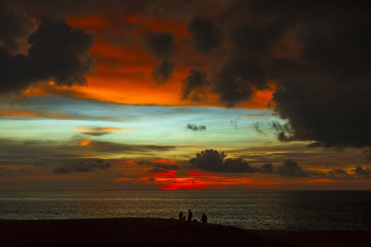 Silhouettes of people on the beach, watching the colorful sunset