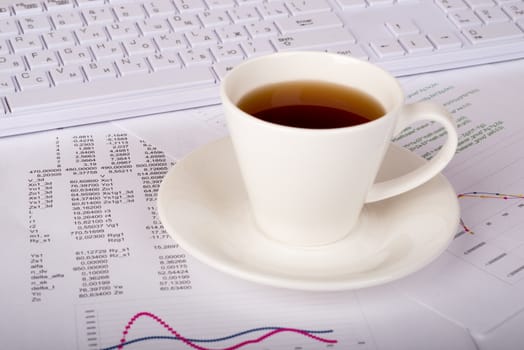 White keyboard with coffee cup and documents, side view