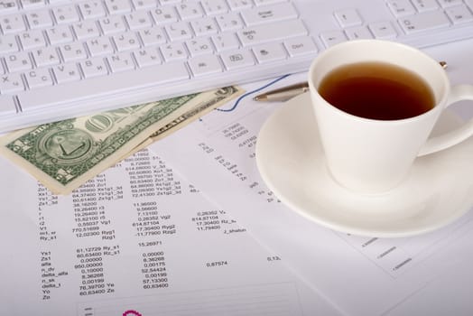 White keyboard with coffee cup, dollars and documents, side view