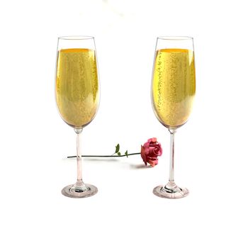 Two glasses of good champagne and a rose on a white background which symbolizes love.