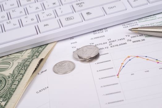 White keyboard with coins, dollars and documents, side view