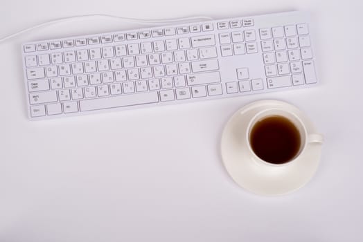 White keyboard and coffee cup on isolated white background. Closed up view