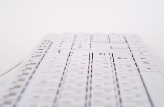White computer keyboard with wire on isolated white background, close up view