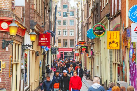 AMSTERDAM - APRIL 16: Narrow street crowded with tourists on April 16, 2015 in Amsterdam, Netherlands. It's the capital city and most populous city of the Kingdom of the Netherlands.
