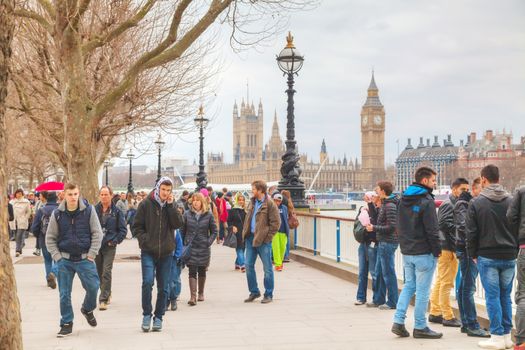 LONDON - APRIL 4: Thames riverbank crowded with tourists on April 4, 2015 in London, UK. London is a popular centre for tourism, one of its prime industries, employing the equivalent of 350,000 full-time workers.