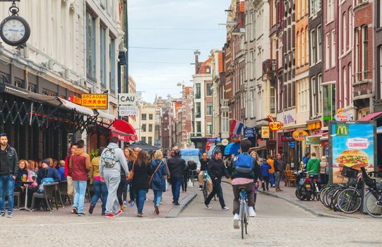 AMSTERDAM - APRIL 16: Narrow street crowded with tourists on April 16, 2015 in Amsterdam, Netherlands. It's the capital city and most populous city of the Kingdom of the Netherlands.