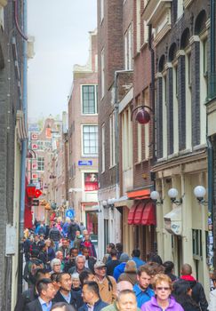AMSTERDAM - APRIL 16: Narrow street crowded with tourists on April 16, 2015 in Amsterdam, Netherlands. It's the capital city and most populous city of the Kingdom of the Netherlands.