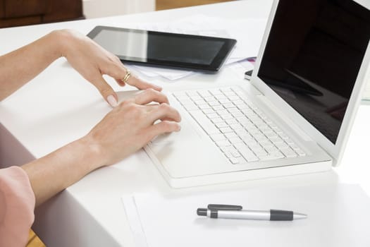 Sitting Young Businesswoman Writing on a Paper While Looking at her Laptop Computer Seriously.