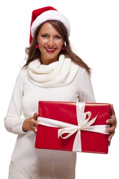 Pretty woman in a festive red Santa hat with a large matching red Christmas gift tied with a ribbon and bow holding it in front of her with a happy smile showing it to the camera, on white