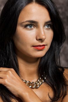 Close up Pretty Young Woman with long Black Hair, Wearing Red. Looking at Right Frame. Captured with Abstract Brown Background.