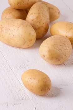 Farm fresh washed whole potatoes for a healthy nutritious cooking ingredient on white painted wooden boards