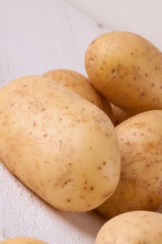 Farm fresh washed whole potatoes for a healthy nutritious cooking ingredient on white painted wooden boards