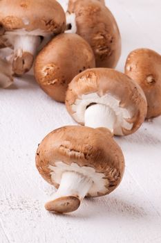 Fresh brown portobello or agaricus mushrooms on a white counter ready for use as a savory cooking ingredient or in vegetarian and vegan cuisine