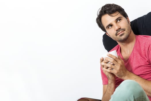 Young Man in Casual Clothing Sitting on Black Chair While Reading a Book and Holding a Glass of Drink.