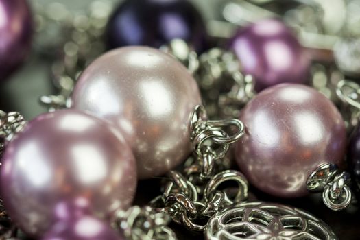 Close up of three attractive shiny purple beads attached by silver chains on an item of jewellery in a fashion and handicraft concept