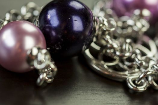 Close up of three attractive shiny purple beads attached by silver chains on an item of jewellery in a fashion and handicraft concept