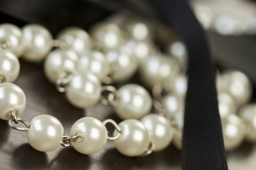String of shiny grey beads winding through the frame in a close up view of fashion jewellery with selective focus to two beads