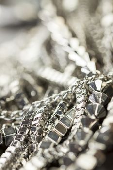 Pile of assorted silver chains with shiny box chains, cube chains and ordinary linked chain on a grey background conceptual of fashion jewellery