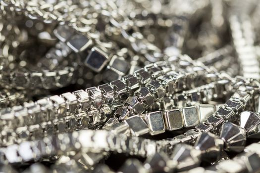 Pile of assorted silver chains with shiny box chains, cube chains and ordinary linked chain on a grey background conceptual of fashion jewellery