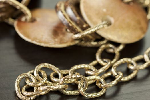 Scratched and tarnished old silver jewellery with two flat discs flanking a ring suspended on an oval link chain, close up view on a grey background