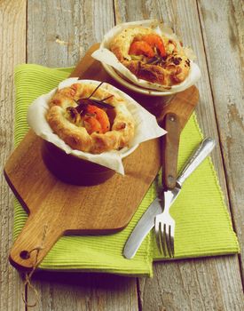 Puff Pastry Snacks with Roasted Shrimps, Leek and Cheese Oven-Baked in Ramekin on Wooden Cutting Board with Fork and Knife. Retro Styled