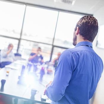 Business man making a presentation at office. Business executive delivering a presentation to his colleagues during meeting or in-house business training, explaining business plans to his employees.