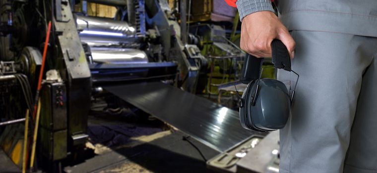 Worker with protective headphone at man hands at industrial factory