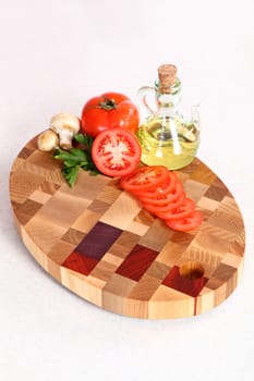 the cut tomato, vegetable oil and field mushrooms on a chopping board