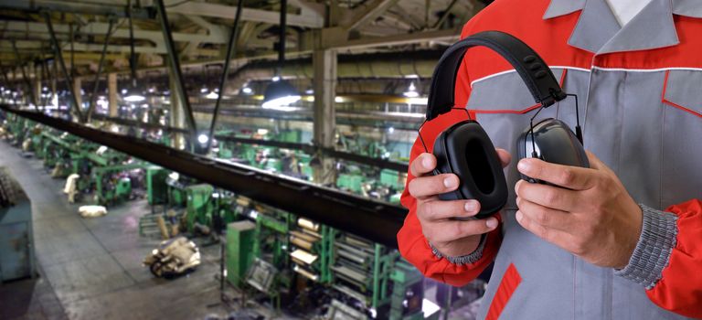 Worker with protective headphone at man hands at industrial factory