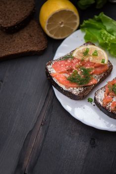 Homemade sandwich with salmon and rye bread , butter lemon, and lettuce for breakfast