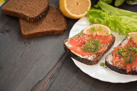 Homemade sandwich with salmon and rye bread , butter lemon, and lettuce for breakfast