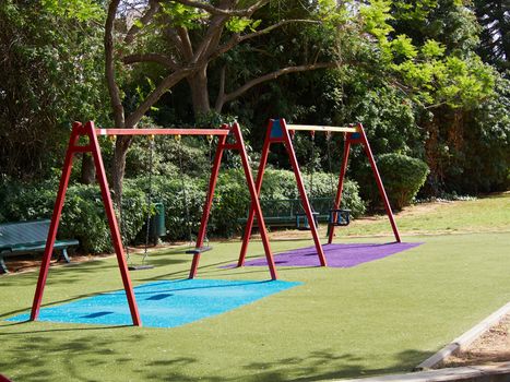 Colorful playground swing in a green city town park  