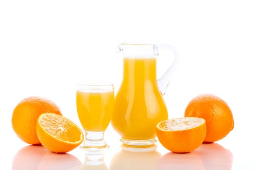 Orange juice in pitcher and oranges. Isolated on white background