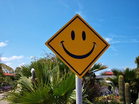 Conceptual funny road sign with a smiley face with clear blue sky background