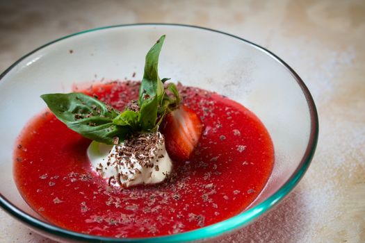 strawberry soup with ice cream and mint on a plate decorated fresh strawberries and chocolate