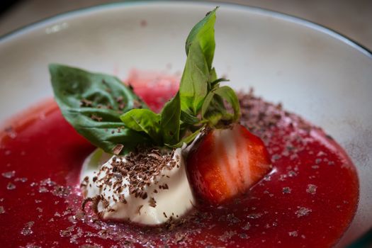 strawberry soup with ice cream and mint on a plate decorated fresh strawberries and chocolate