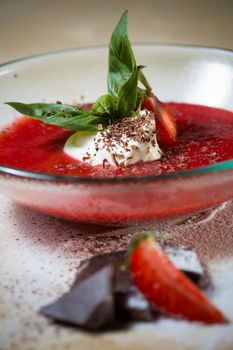 strawberry soup with ice cream and mint on a plate decorated fresh strawberries and chocolate