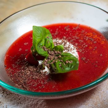 strawberry soup with ice cream and mint on a plate decorated fresh strawberries and chocolate