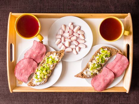 Homemade breakfast: bread with ham, onions, radish and tea, prepared for a couple, top