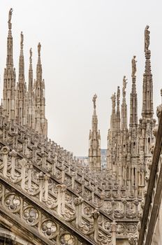 Detail vertical view of stone sculptures on roofs of Duomo Milano, Italy