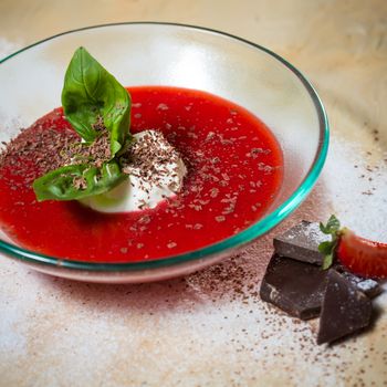 strawberry soup with ice cream and mint on a plate decorated fresh strawberries and chocolate