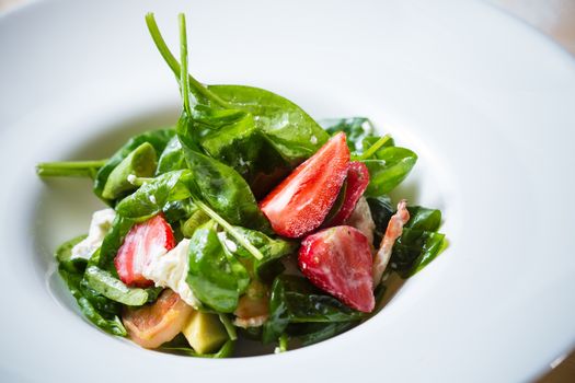 Fresh Salad with strawberries, goat cheese and shrimps dressed with balsamic vinegar and olive oil