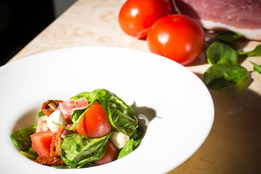 Salad with strawberry, prosciutto, herbs, cottage cheese and blackberry balsamic vinegar. Shallow dof.